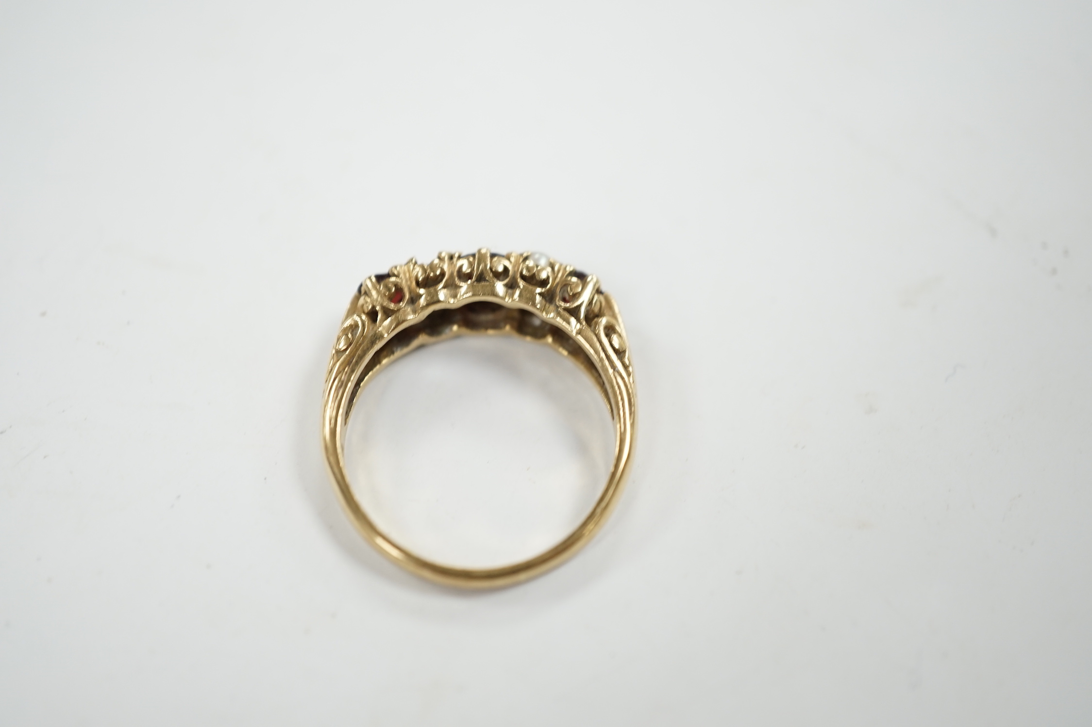 A modern 9ct gold, three stone garnet and four stone split pearl set half hoop ring (two pearls missing), size S/T, gross weight 3.8 grams.